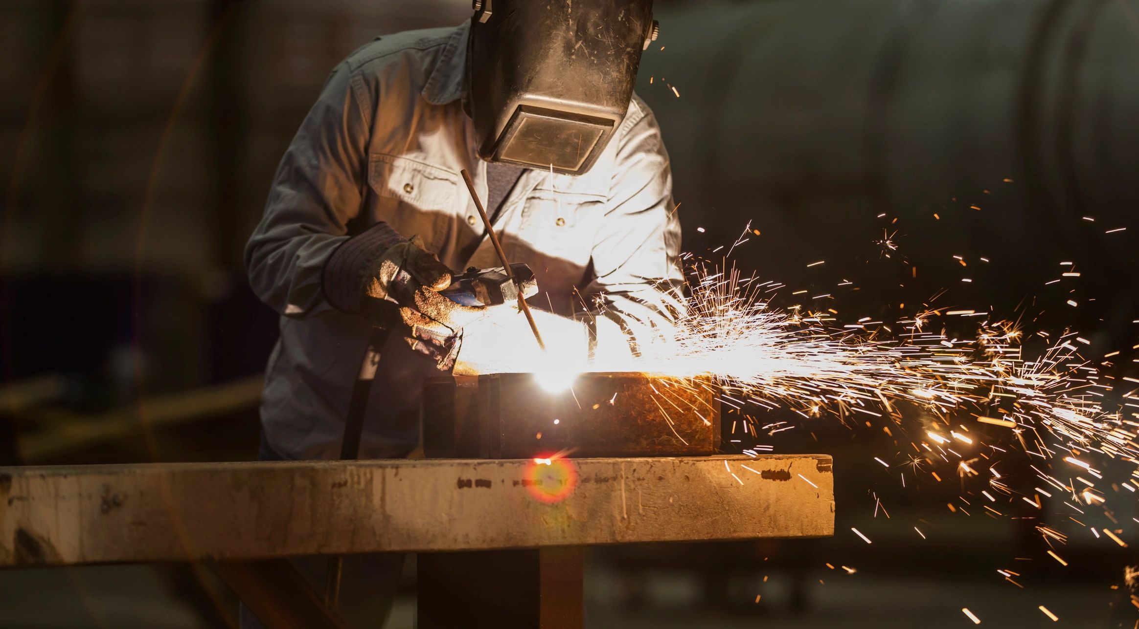 Welder working with sparks flying in a workshop