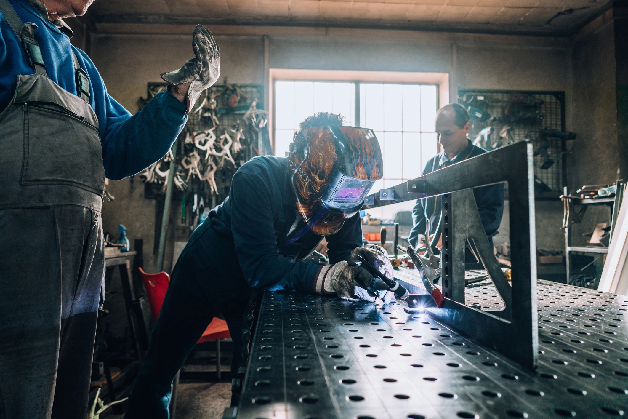 Welder and colleague working together on a metal fabrication project in a workshop