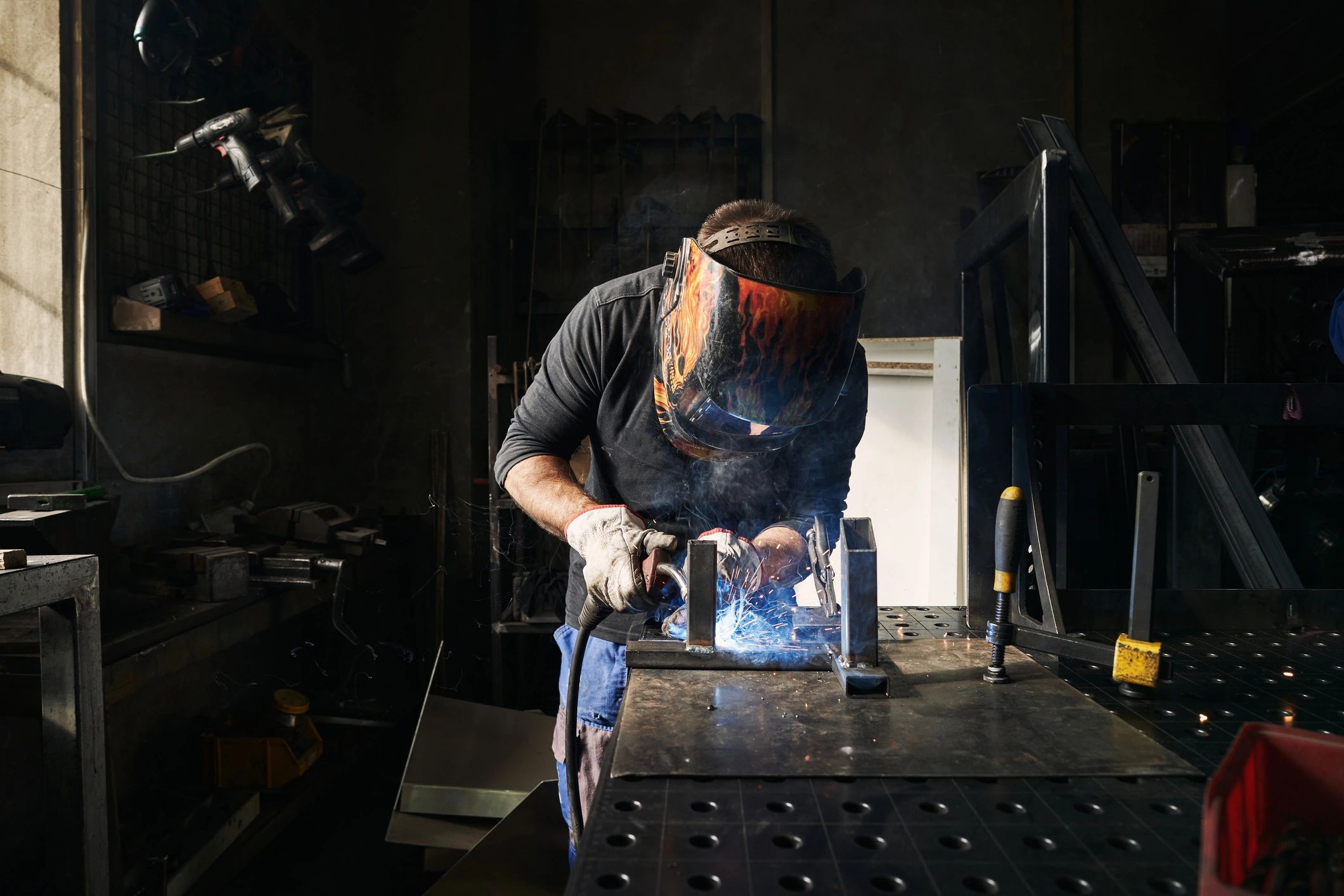 Welder working at a metal workshop wearing protective gear