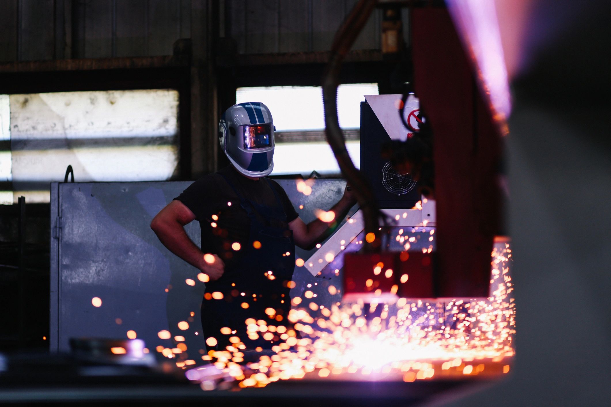 Welder in protective helmet working in an industrial workshop