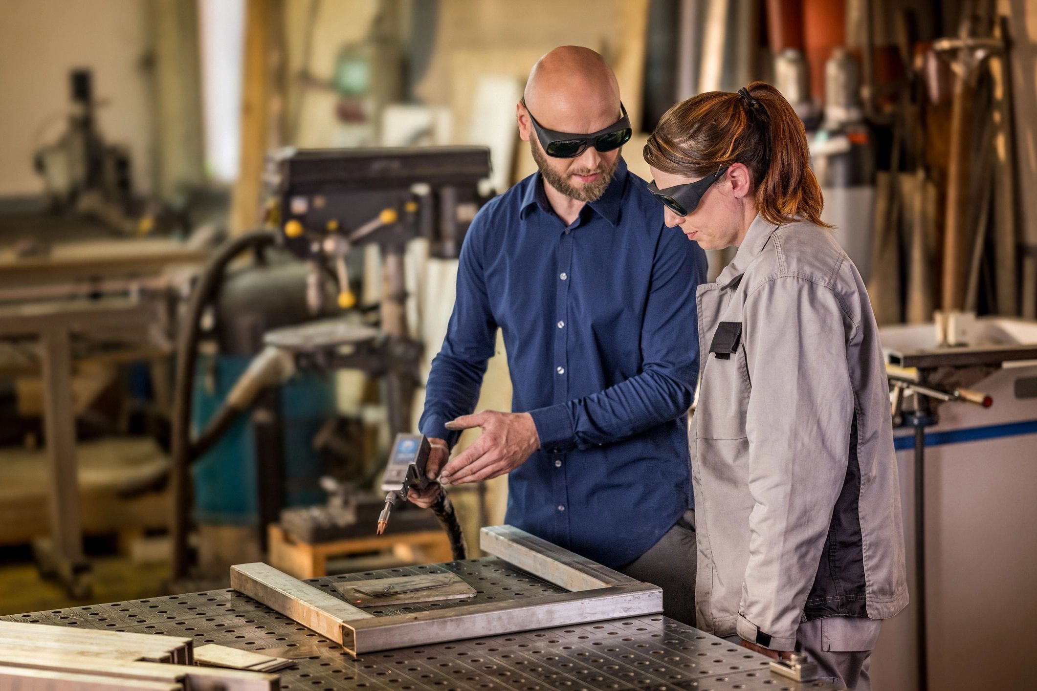 Instructor demonstrating welding technique at an industrial workbench